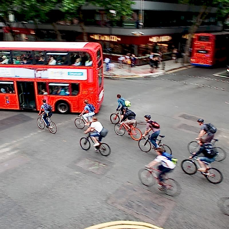 People cycling across junction with bus