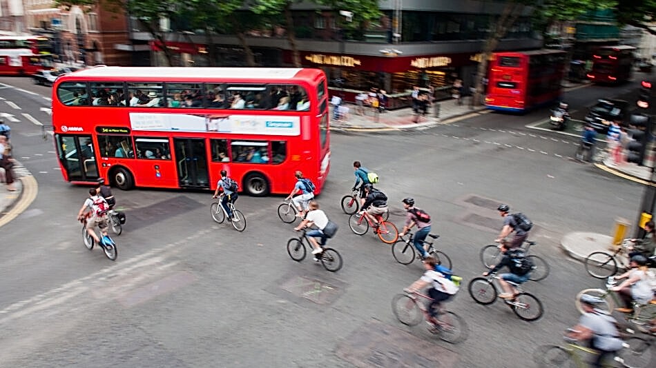 Group of people cycling through junction with bus